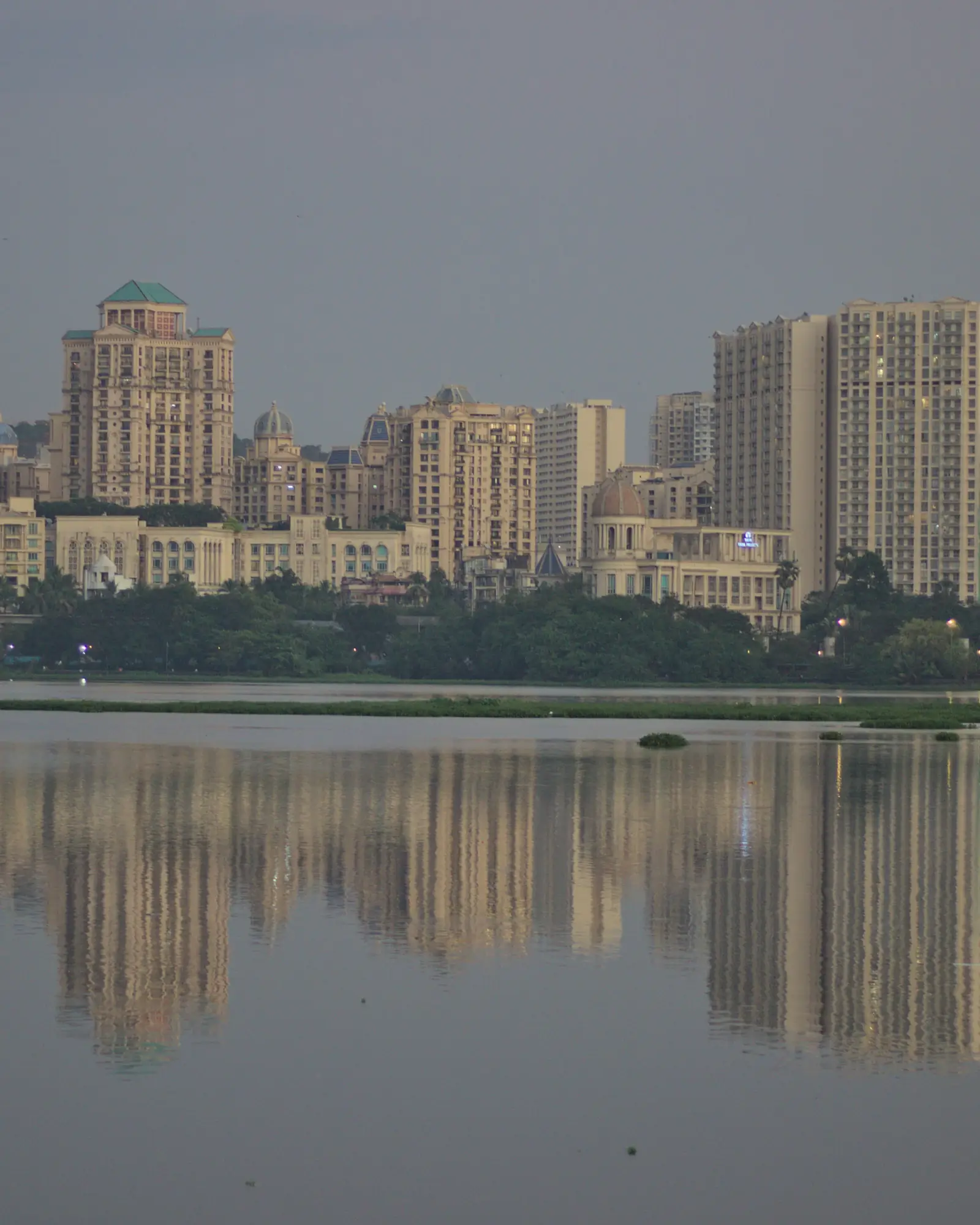 Apartment towers of Hiranandani Gardens reflected in Powai Lake at dusk, Mumbai