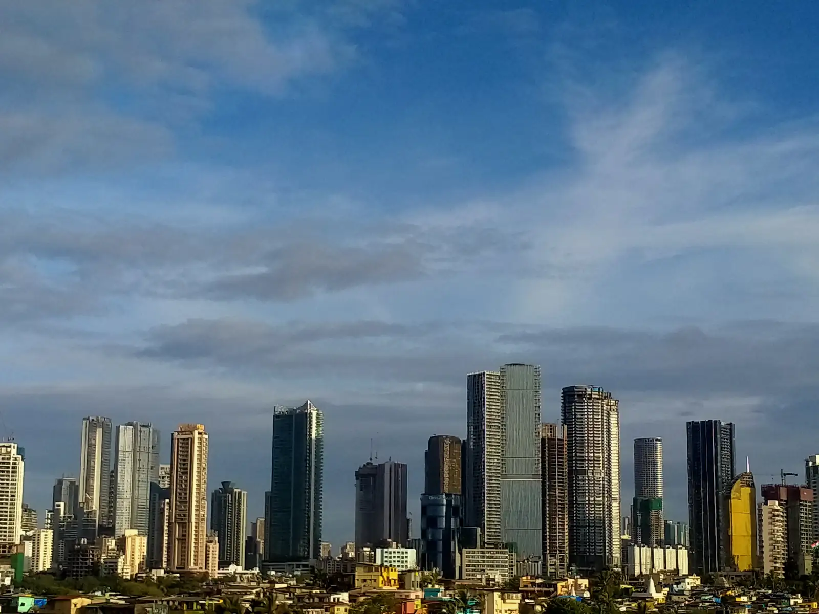 High-rise towers on the Mumbai skyline under a cloudy blue sky